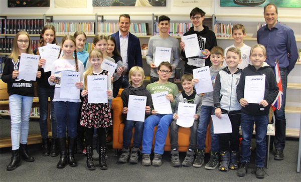 Schüler mit Zeugnissen in der Schulbibliothek